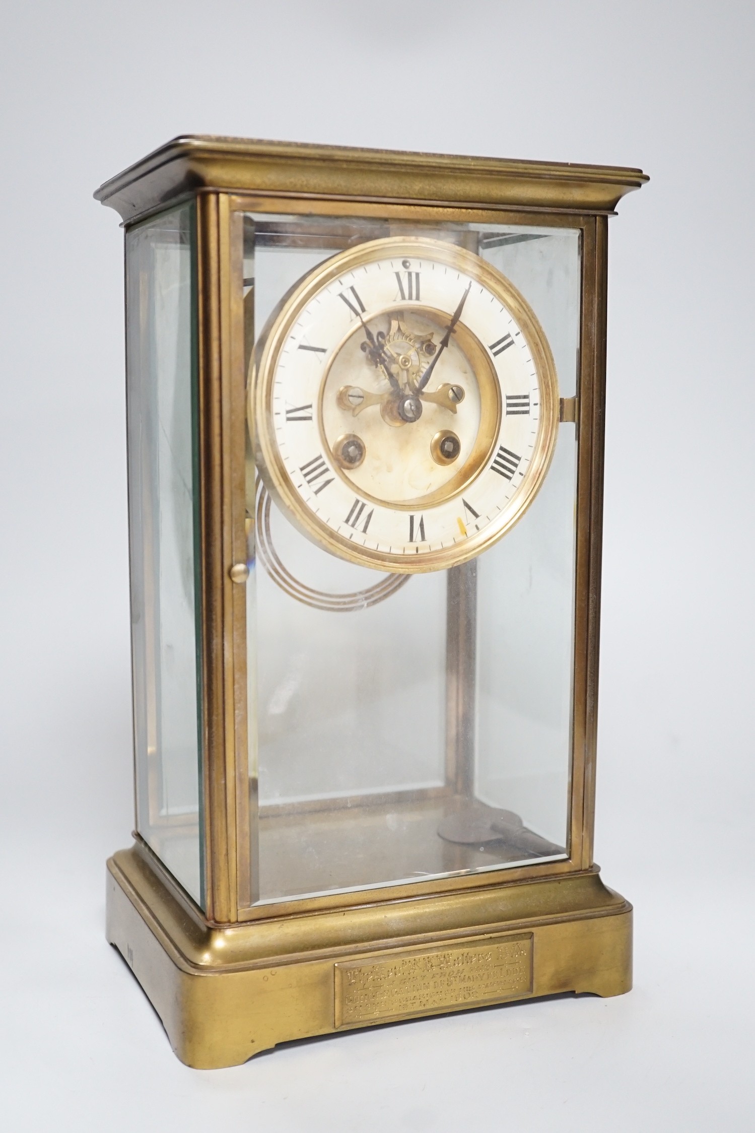An Edwardian brass four-glass mantel clock with pendulum, presentation plaque to base, 30cm tall
